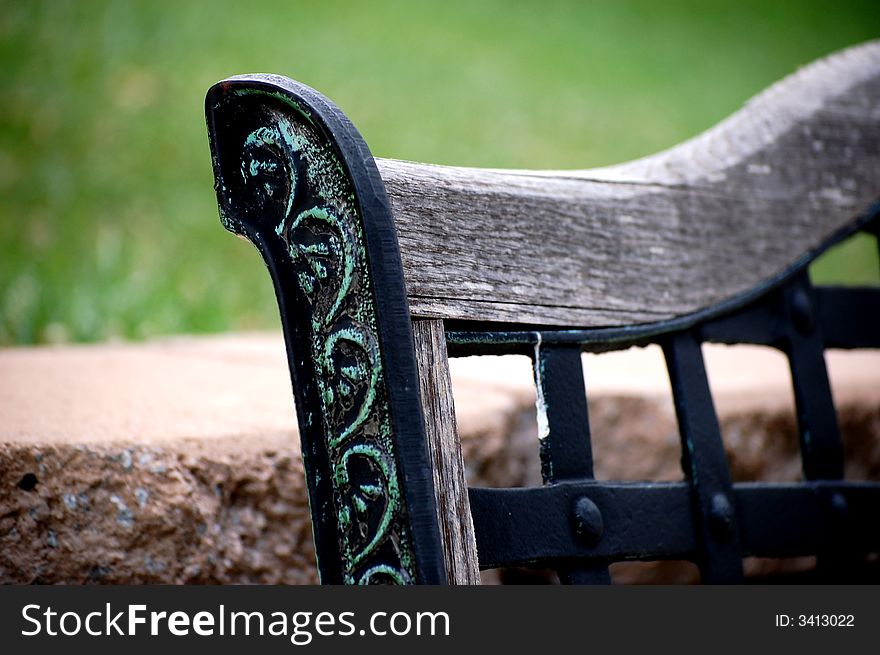 Wrought iron and wooden bench against stone wall in the garden. Wrought iron and wooden bench against stone wall in the garden