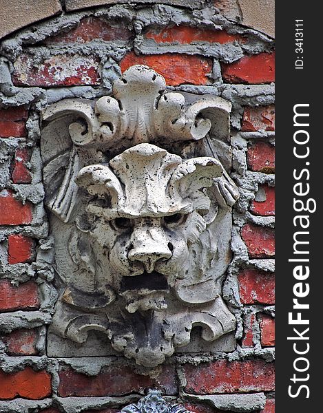 A stone lion looking out from brick wall