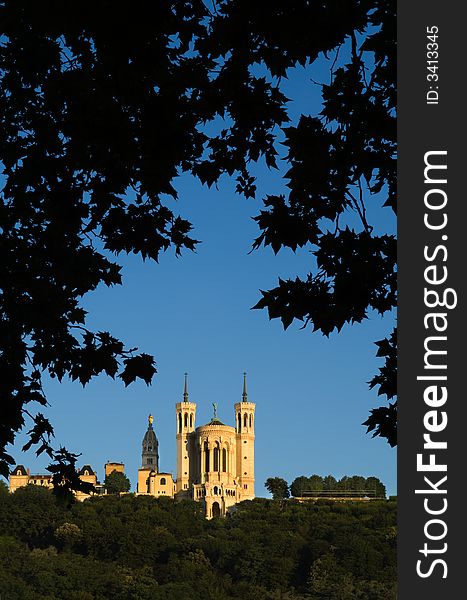 The basilica of Notre Dame de Fourviere, in Lyon, France, framed by foreground trees