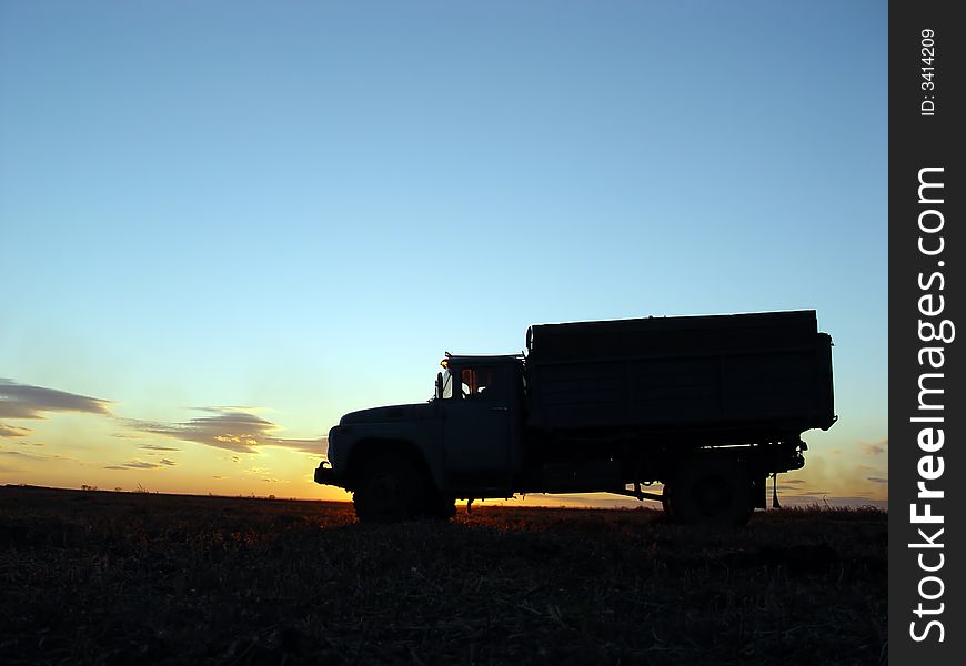 Silhouette of lorry in the filed with sunset background