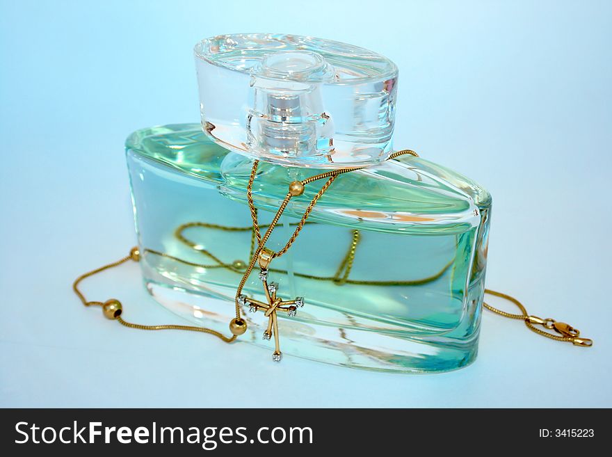 Bottle of perfume and jewels isolated on the blue.