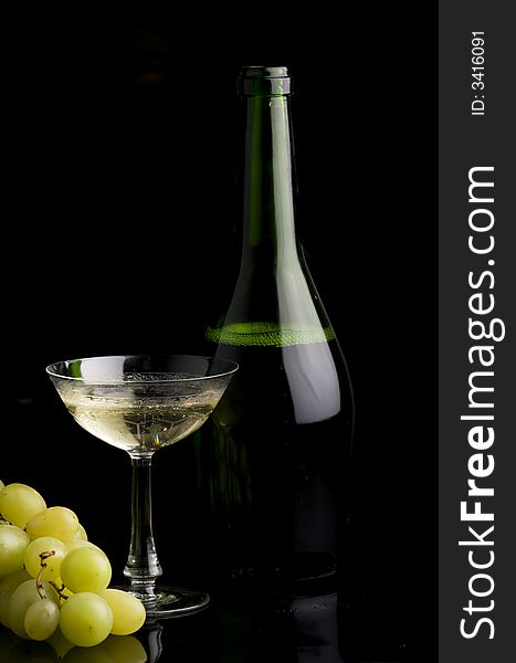 White grape , bottle and a glass full of champagne over a black background. White grape , bottle and a glass full of champagne over a black background