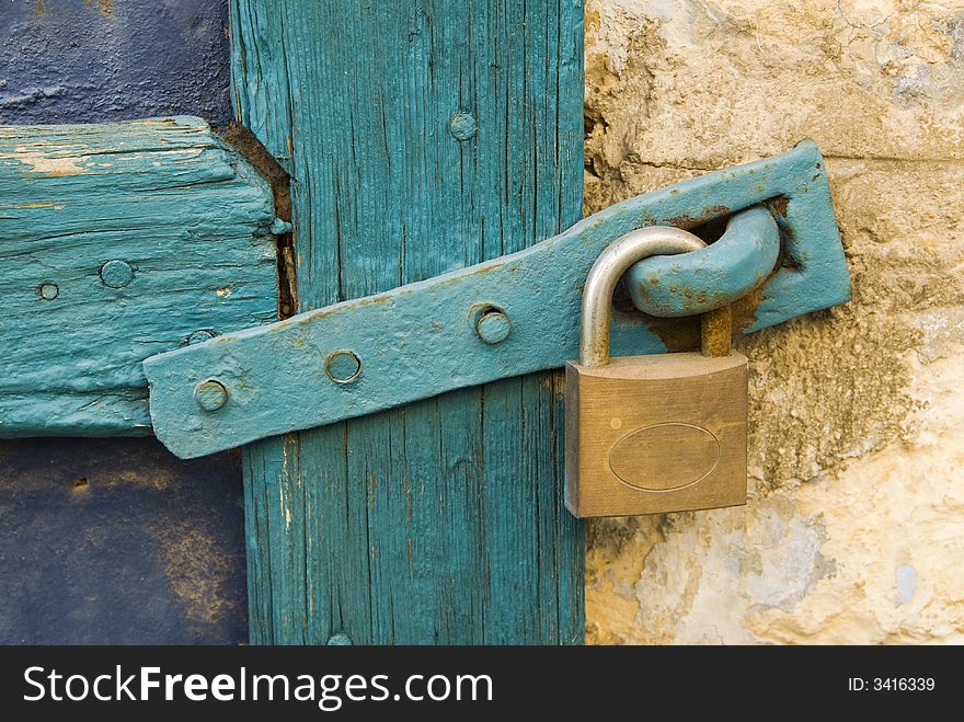 Old lock with a metal clasp on a blue wooden door frame