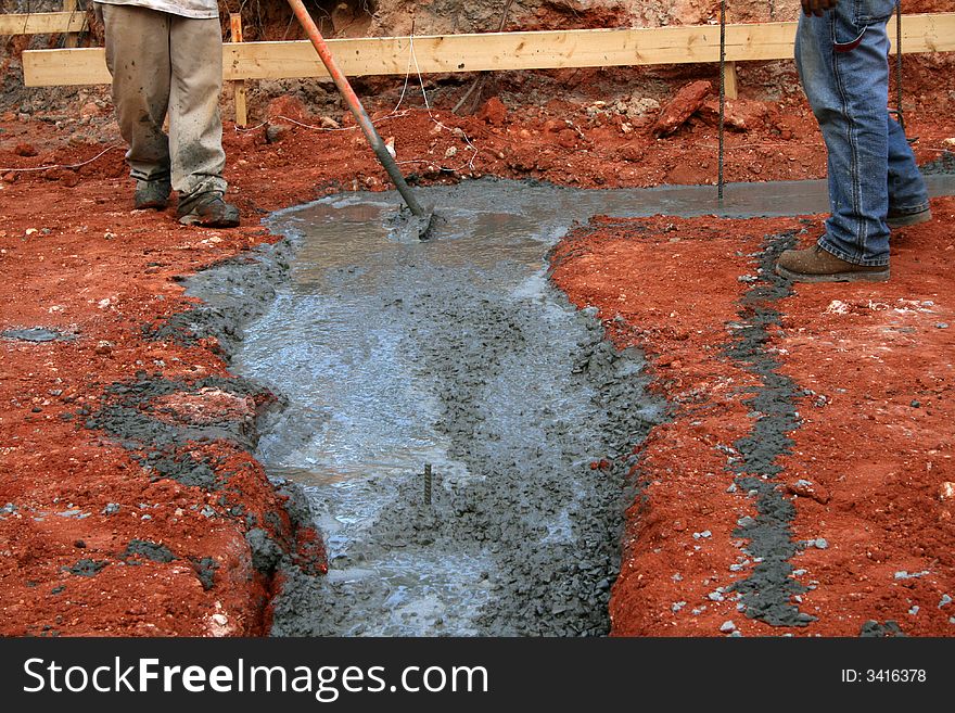 Worker setting footer on new home construction site with plans