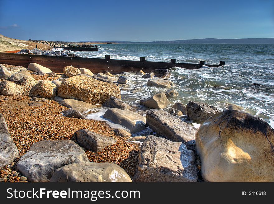 HDR Image of Groynes protecting the coast with rugged rocks in foreground. HDR Image of Groynes protecting the coast with rugged rocks in foreground