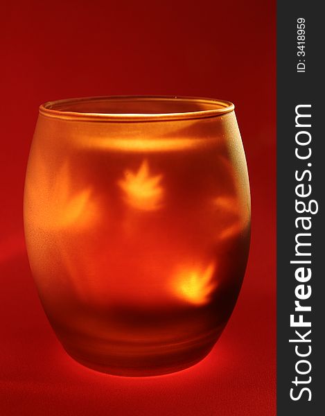 Candle in glass holder, with reflecting light shapes