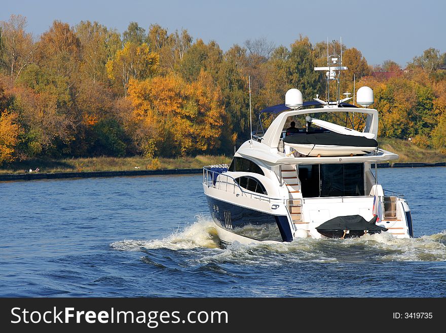 Rear view of sailing luxury yacht on golden autumn scenic background.