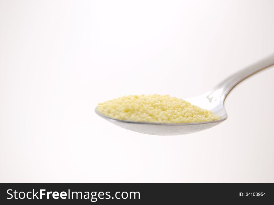 Millet in a spoon on white background.