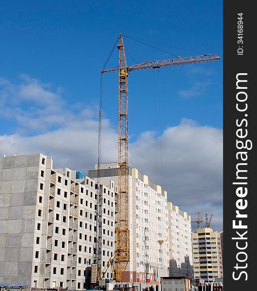 The construction crane and a building under construction surrounded by clouds