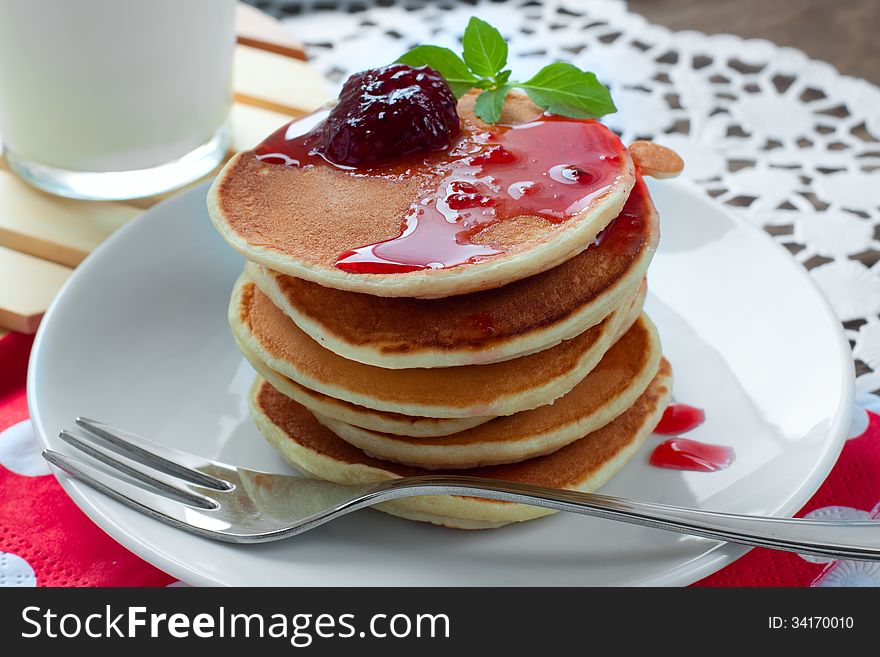Pancakes on a white plate with strawberry jam