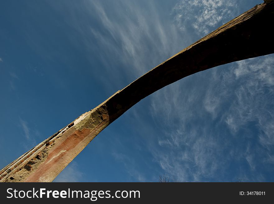 Arch of the old ruined building on a background of blue sky. Arch of the old ruined building on a background of blue sky