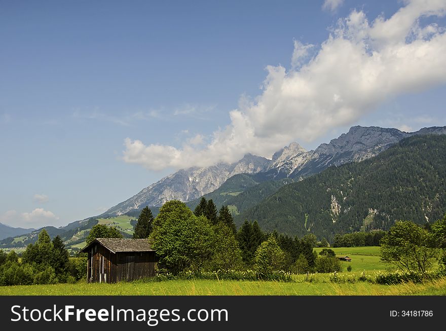 An Old Wooden Barn On The Background Of  The Alps Mountains