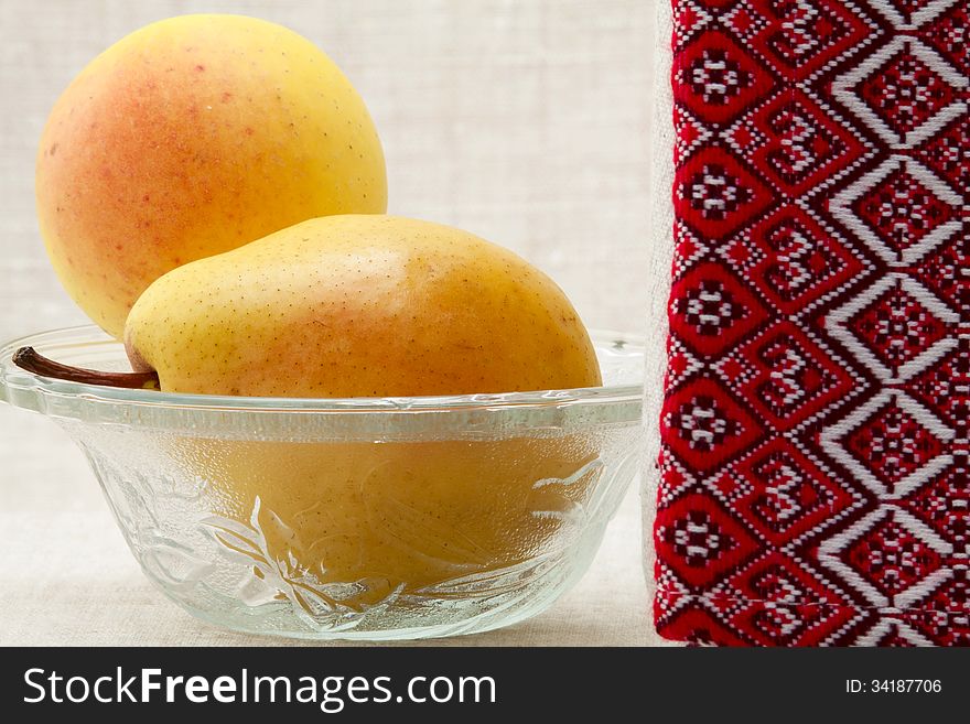 Ripe pears in a glass bowl and towel with ornament