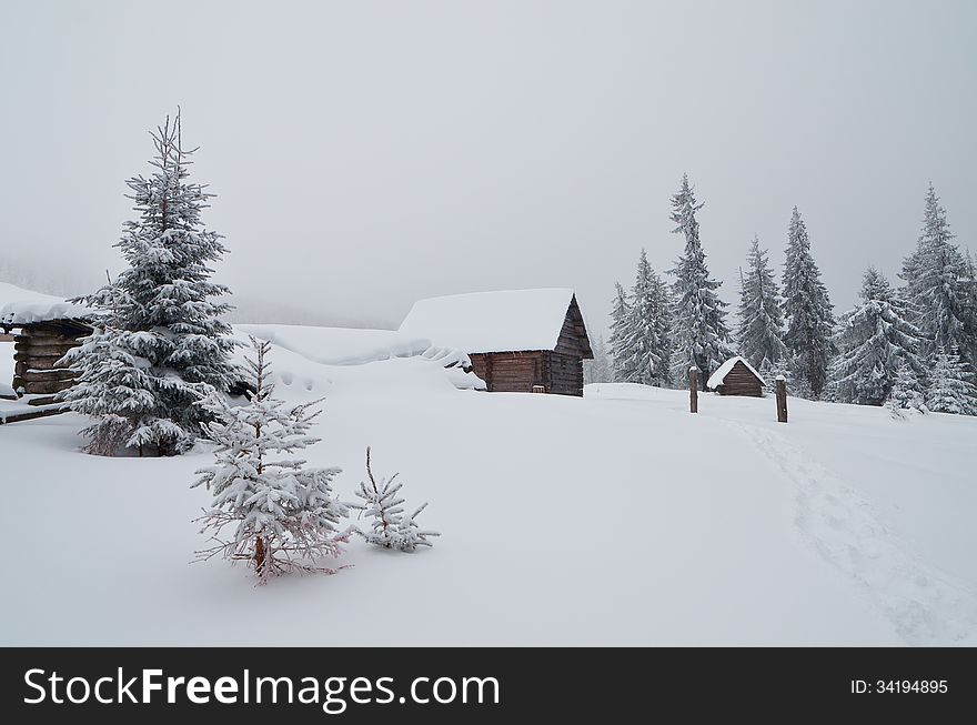 Wooden cabins in a mountain valley. Winter landscape. Ukraine, Carpathians. Wooden cabins in a mountain valley. Winter landscape. Ukraine, Carpathians