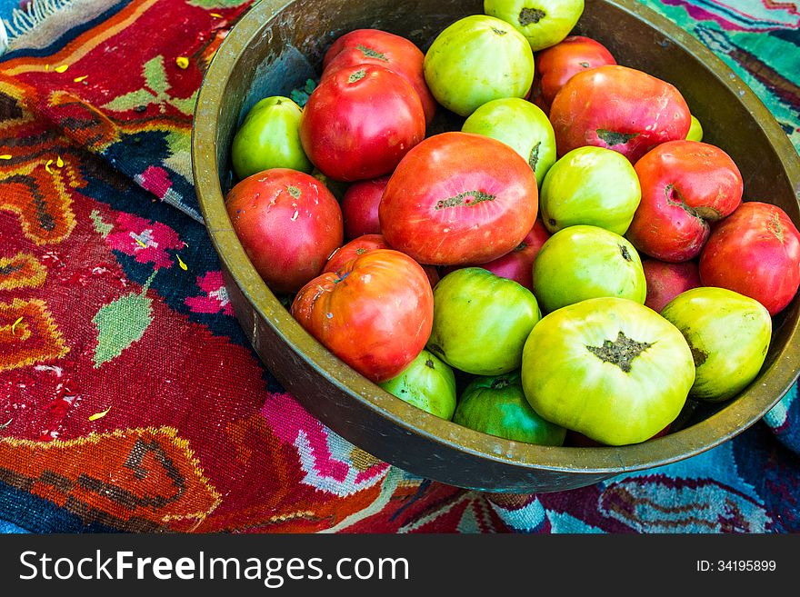 Dish with red and green tomatoes on ethnic carpet