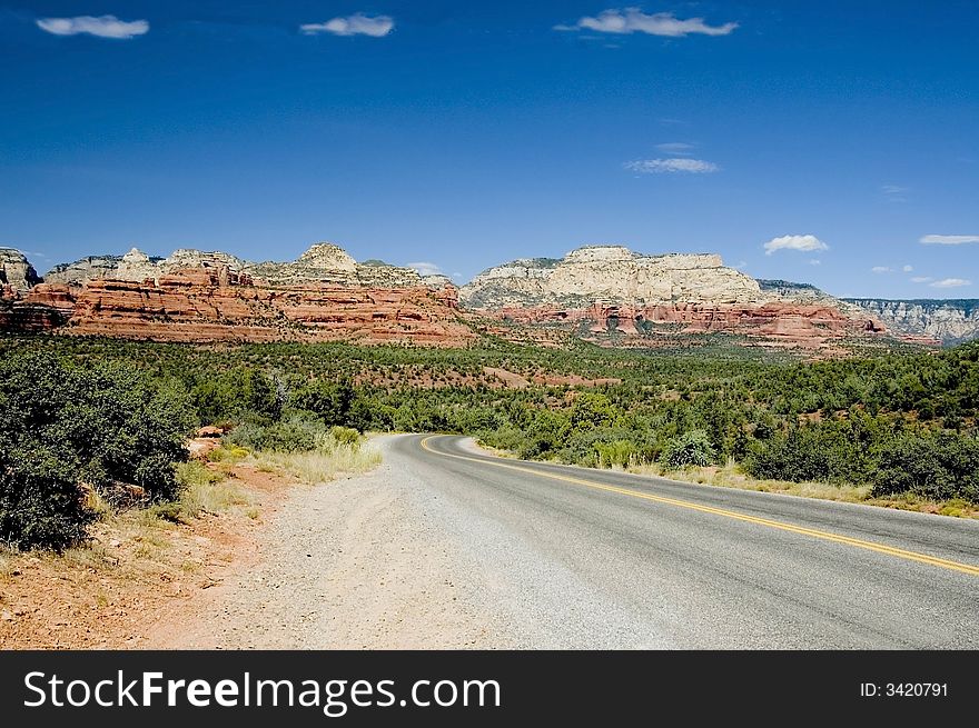 A picture of a highway leading to the mountains of sedona in the background. A picture of a highway leading to the mountains of sedona in the background