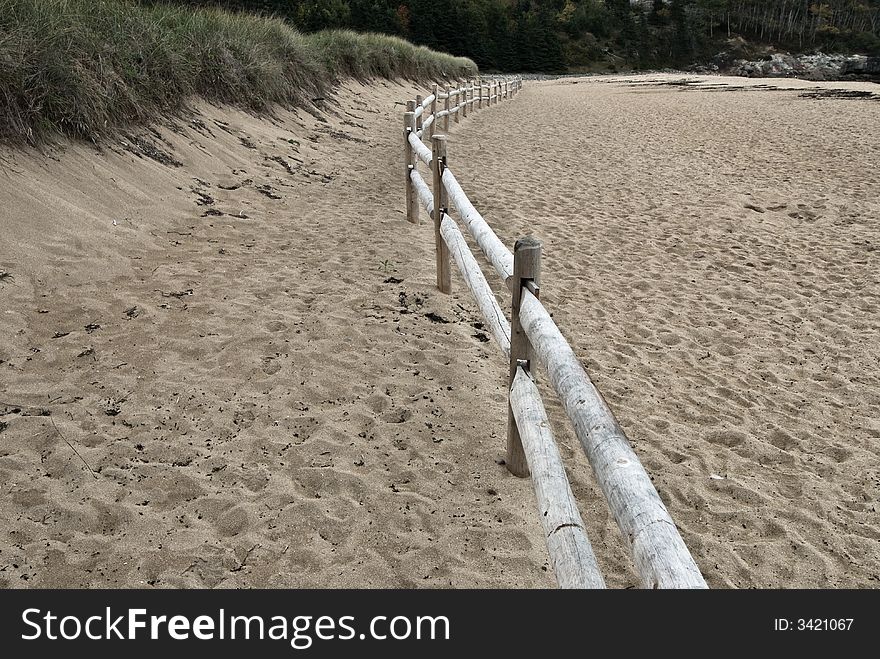 Wooden fence waving through a sandy beach among sand dunes. Wooden fence waving through a sandy beach among sand dunes