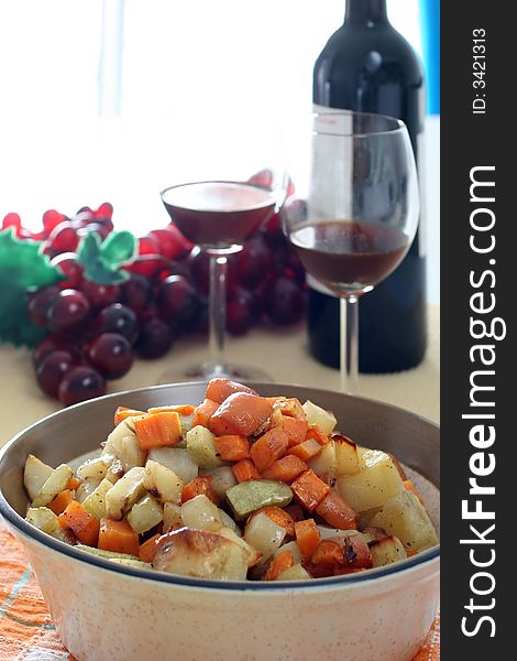 Mixed potatoes vegetarian dish with red wine and grapes in the background. Mixed potatoes vegetarian dish with red wine and grapes in the background