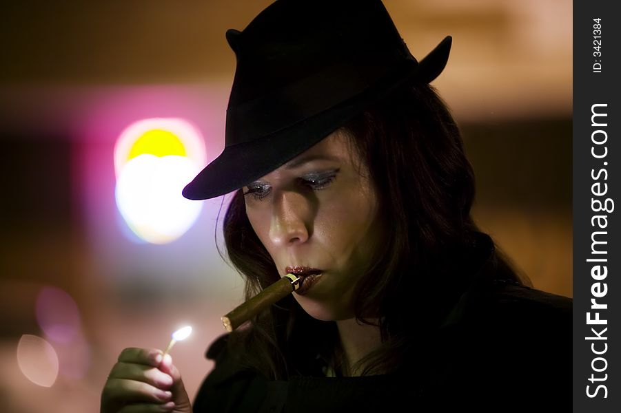 Woman in a fedora lighting a cigar with a match. Woman in a fedora lighting a cigar with a match.