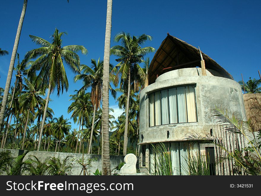 Modern house near tropical beach with palm trees and blues sky background. Modern house near tropical beach with palm trees and blues sky background.