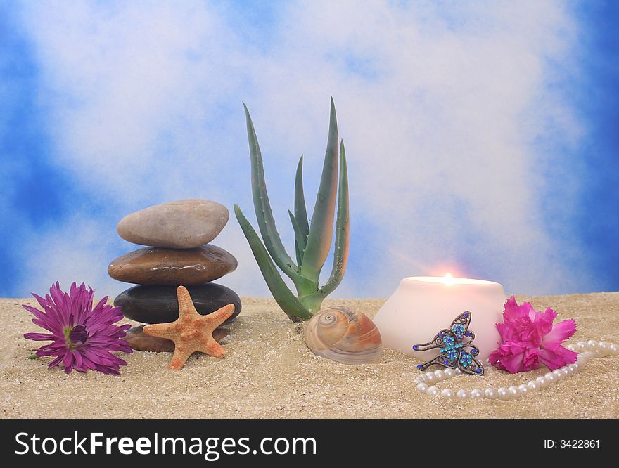 Jewelry and Plant on Sand With Candle and Blue Sky Background