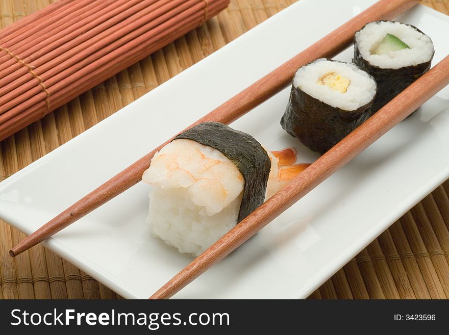 Japanese sushi with chopsticks on a white plate