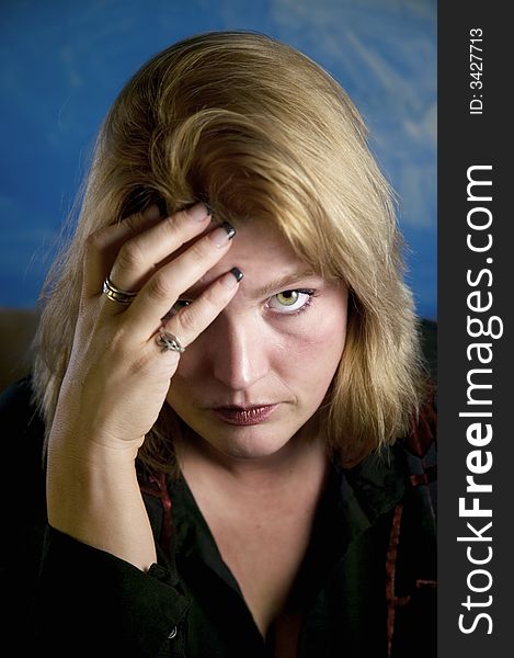 Close up of blonde woman in a studio setting touching her temple. Close up of blonde woman in a studio setting touching her temple.