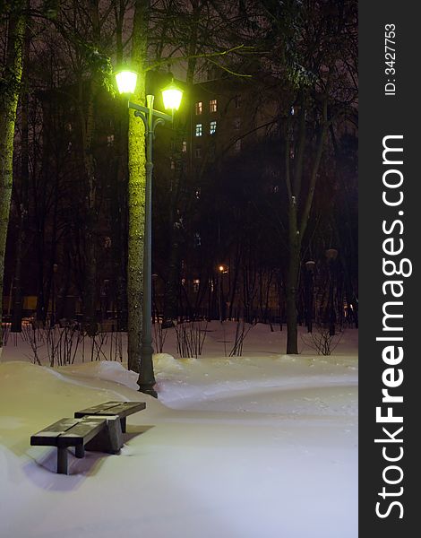 Bench In A Snowy Park At Night