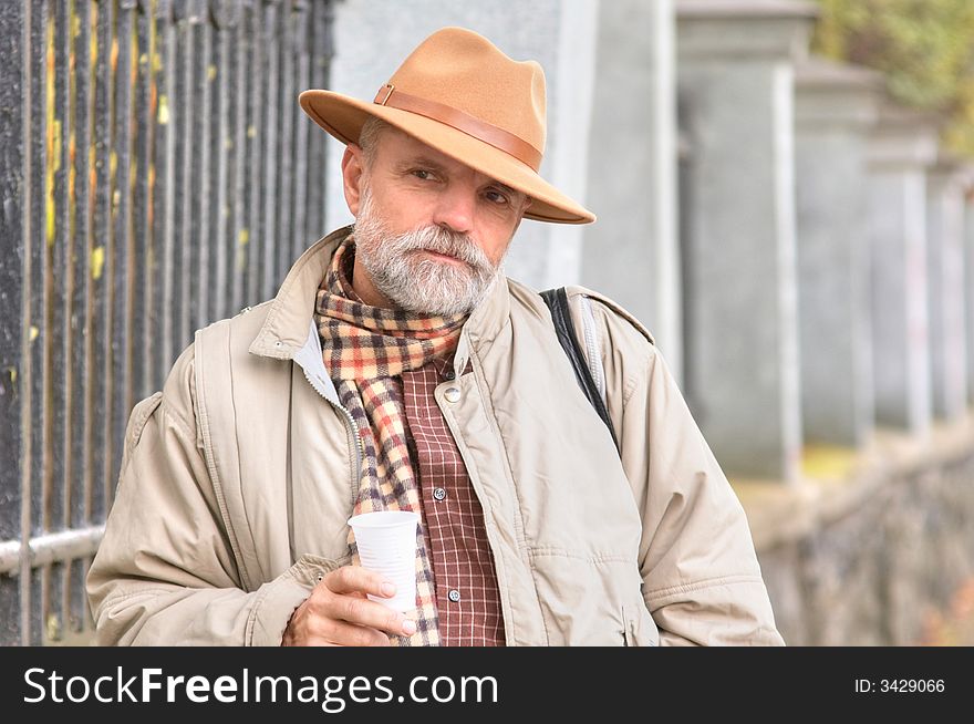 Bearded man in a hat with a plastic glass