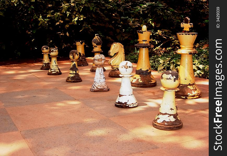 An ancient and ruined pieces of wooden chessmen placed outdoors. An ancient and ruined pieces of wooden chessmen placed outdoors.