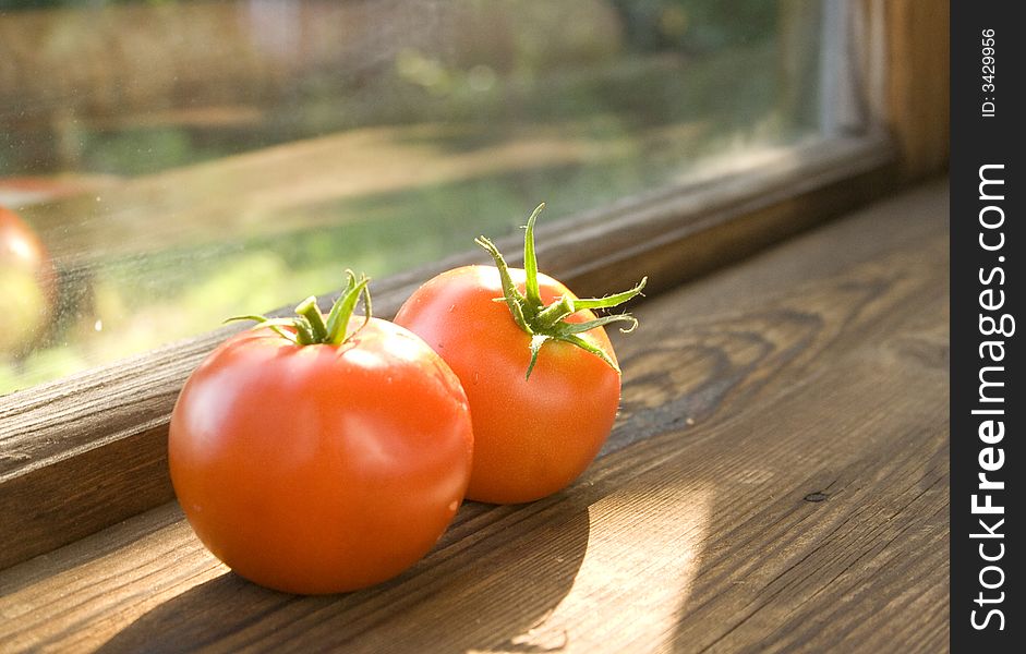 Two tomatoes lies on the window