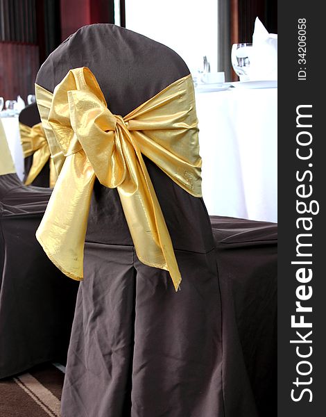 Brown wedding chairs decorated with golden bows. Brown wedding chairs decorated with golden bows