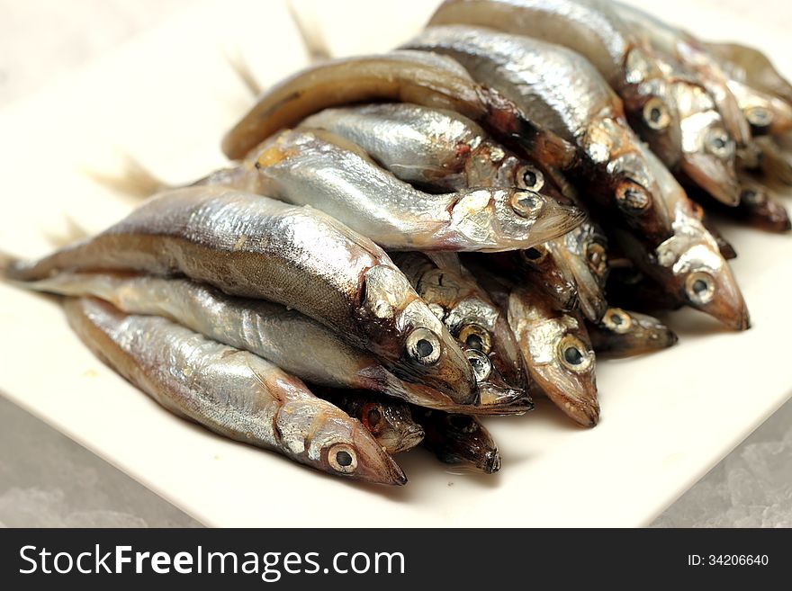 Uncooked trunk small fish on white plate