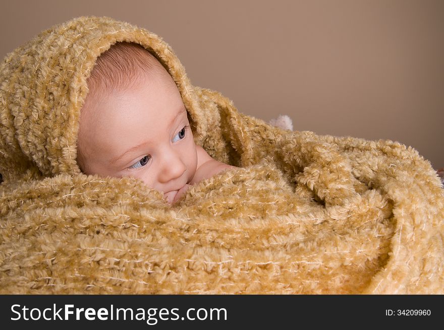 Newborn baby wrapped in light brown soft fluffy cloth on beige background. Newborn baby wrapped in light brown soft fluffy cloth on beige background