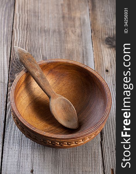 Wooden spoon and a bowl on a wooden background. Wooden spoon and a bowl on a wooden background