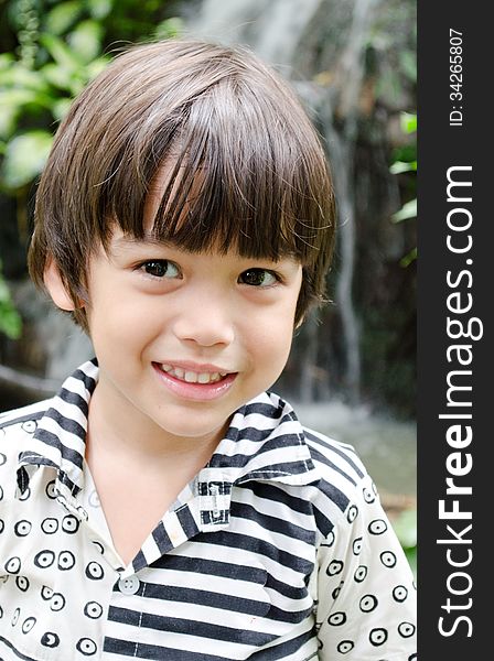 Little Asian boy smiling portrait with water fall background