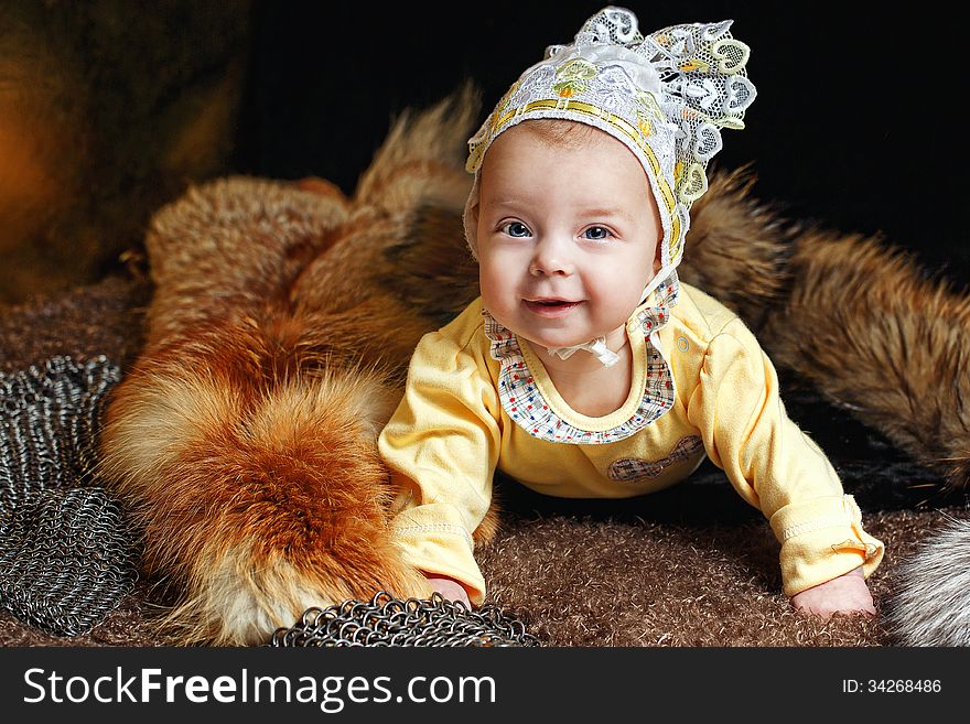 Blue-eyed baby lying on fur litter near the hauberk, fox pelt in the background. Blue-eyed baby lying on fur litter near the hauberk, fox pelt in the background