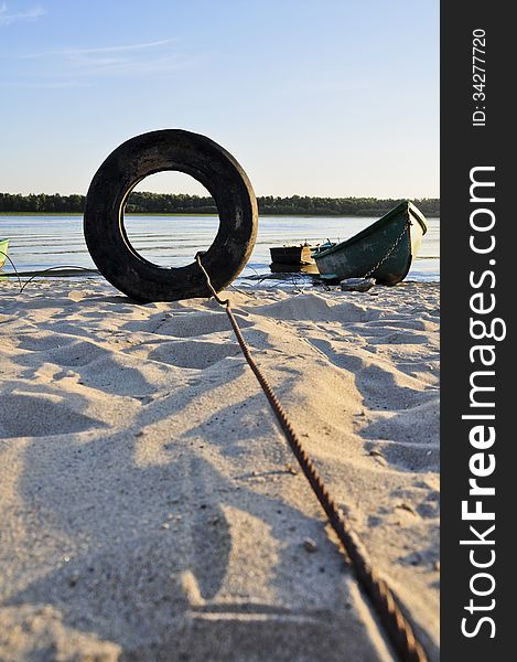 A fisherman boat, tied on Danube shore, through an old tire.