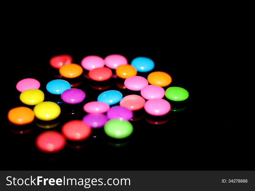 Many colorful chocolate candies against a black background