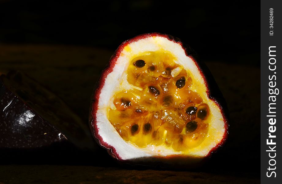 An organically grown passionfruit from tropical Queensland which has been cut into halves and is showing close up details of the bright yellow fleshy pulp and seeds of this very popular fruit. Passion fruit is used in many Australian deserts, puddings, cakes and also as a syrup and a topping. An organically grown passionfruit from tropical Queensland which has been cut into halves and is showing close up details of the bright yellow fleshy pulp and seeds of this very popular fruit. Passion fruit is used in many Australian deserts, puddings, cakes and also as a syrup and a topping.