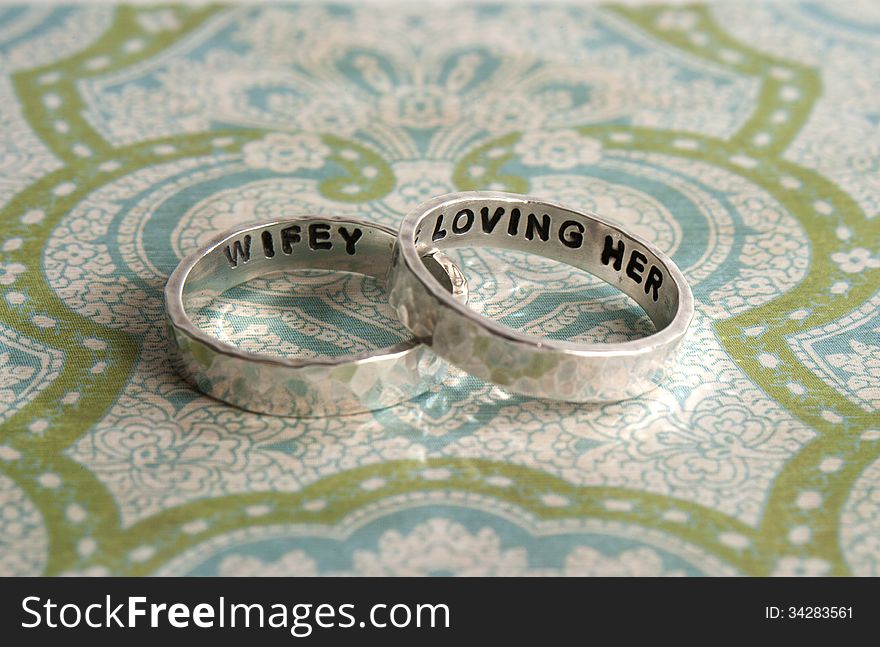 Two hammered sterling silver engagement rings on a piece of decorative paper. Two hammered sterling silver engagement rings on a piece of decorative paper