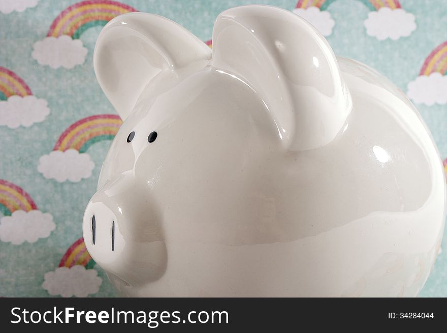 White ceramic piggy bank against a rainbow decorative background. White ceramic piggy bank against a rainbow decorative background