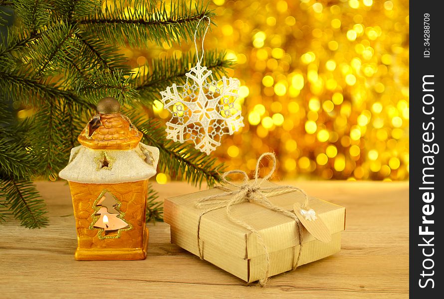 Yellow candle holder with gift in paper wrapping on the golden blurred background. Yellow candle holder with gift in paper wrapping on the golden blurred background