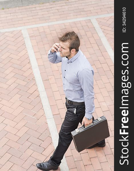 Businessman walking in the street with briefcase and phone. Businessman walking in the street with briefcase and phone.