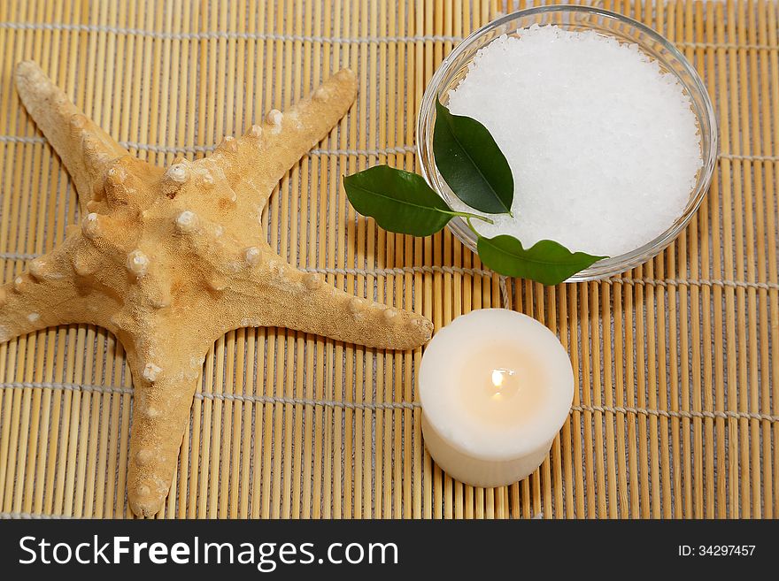 Spa still life - Sea star, candle and sea salt on bamboo mat