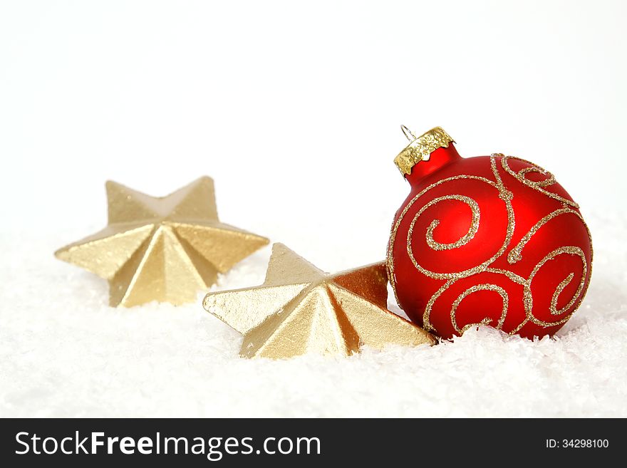 Red-golden bauble and golden stars on the snow. Red-golden bauble and golden stars on the snow
