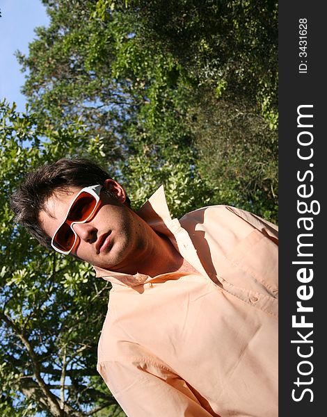 Young male model at an angle against a blue & green nature background