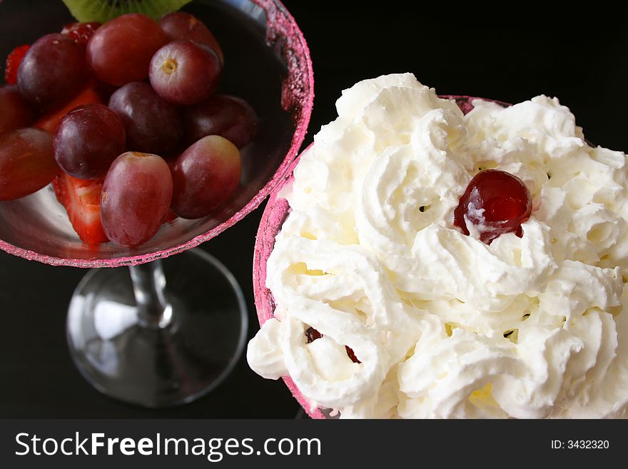 Cherry and cream on top of a fruit salad in glasses. Cherry and cream on top of a fruit salad in glasses