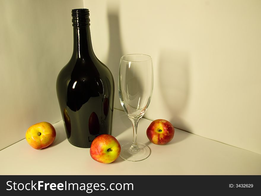 Of Picture depicting a black bottle, empty glass, nectarine with shadows reflecting on white background in fruit-piece style.