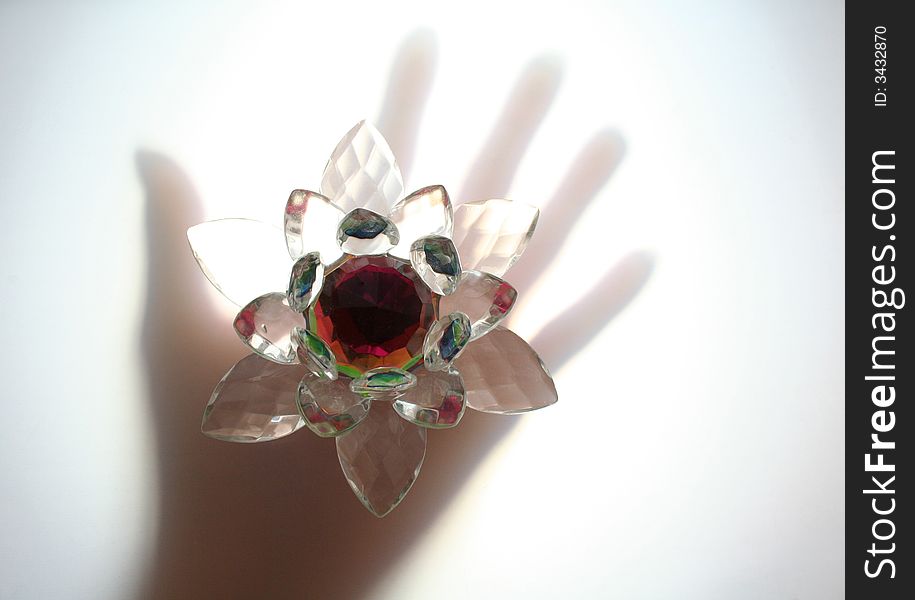 Hand and flower made of glass are lit from bottom